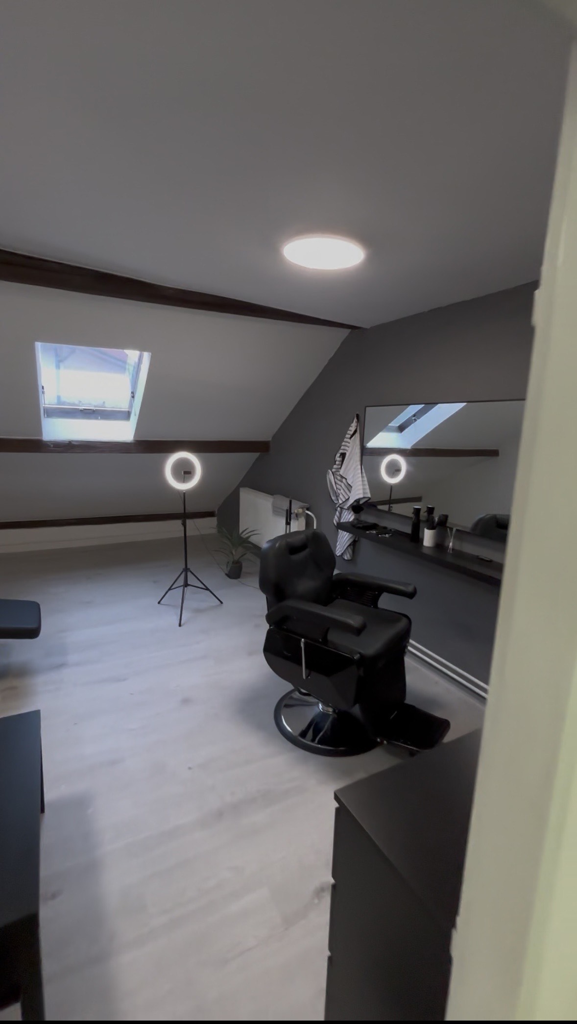 Barberské křeslo ve studiu Petitto Barber — loft s trámy a ring light